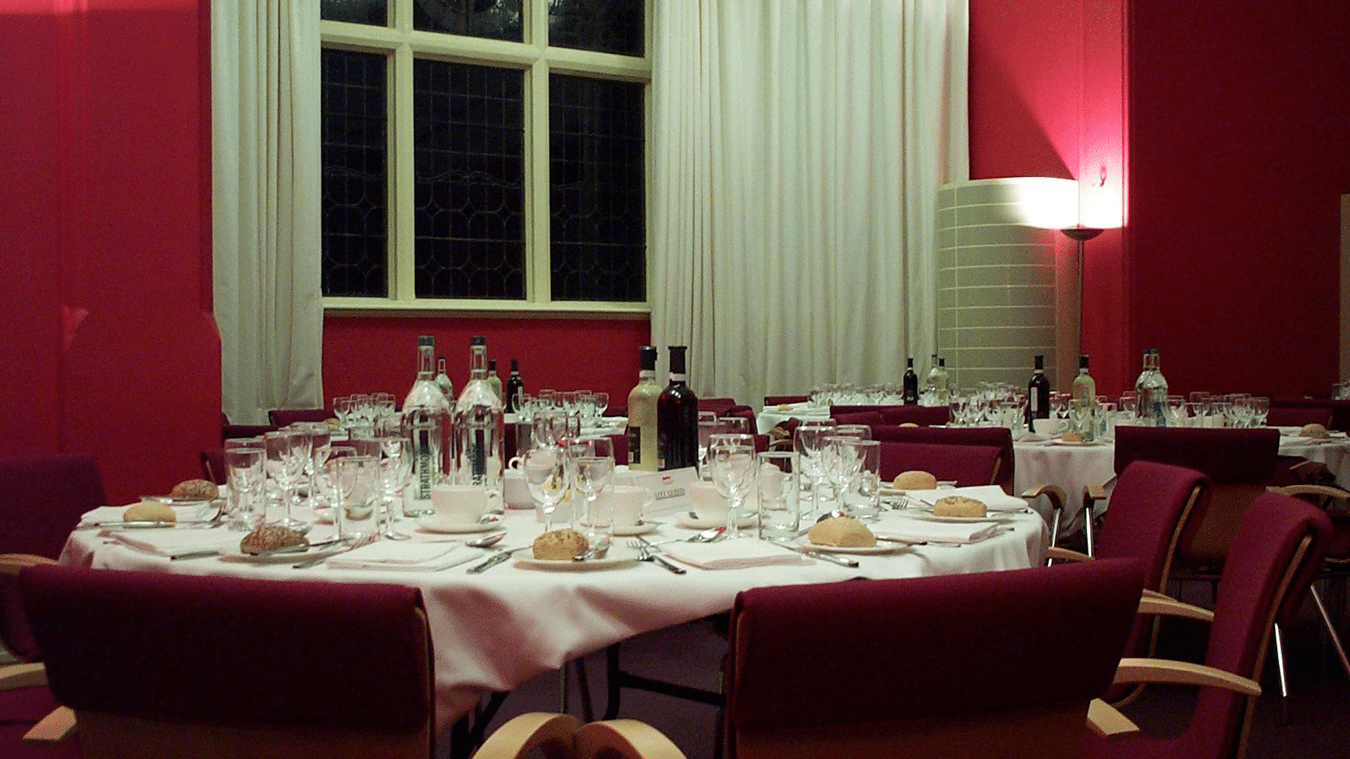 Interior of the Council Chamber. The area is set up with dinner tables with food and wine, the walls are red and look very grand.